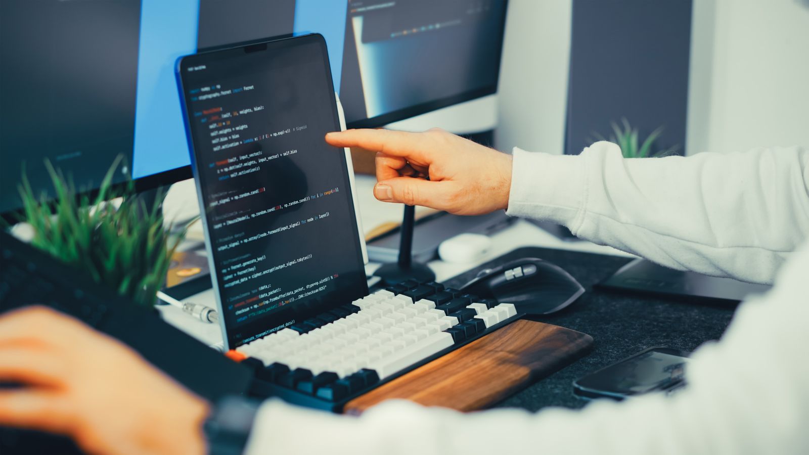 A software developer works across connected code and application screens, illustrating AI-enabled workflow design.