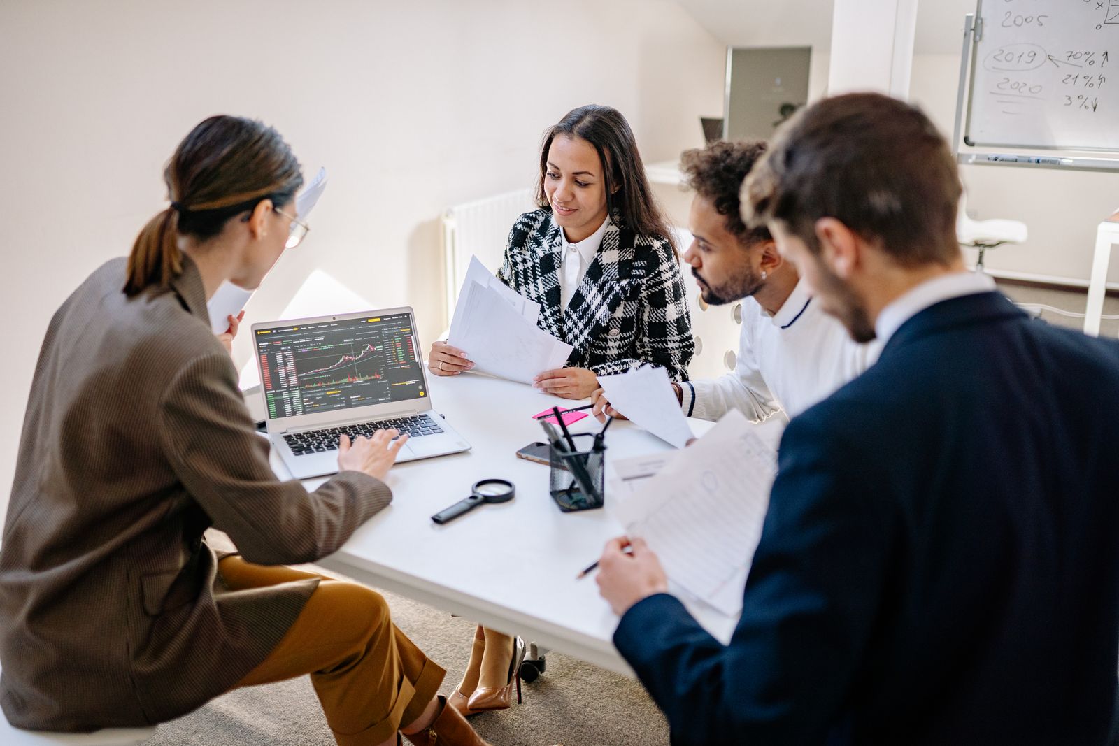 Colleagues analyze a laptop together during a planning meeting, illustrating strategy turning into coordinated execution.